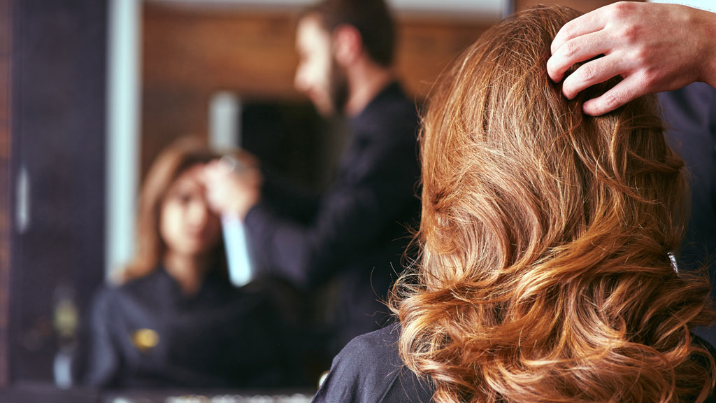 Coiffeur professionnel examinant la texture des cheveux d'une cliente avec attention